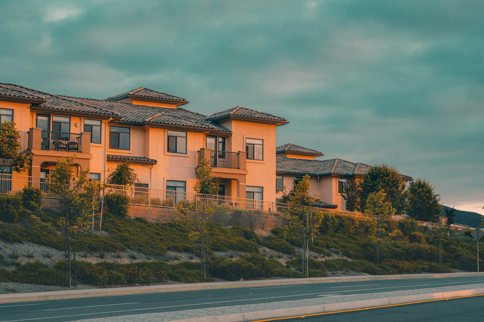 Row of stucco townhomes with tile roofs on a hillside, illustrating multi-unit housing for a first duplex purchase in Wasco