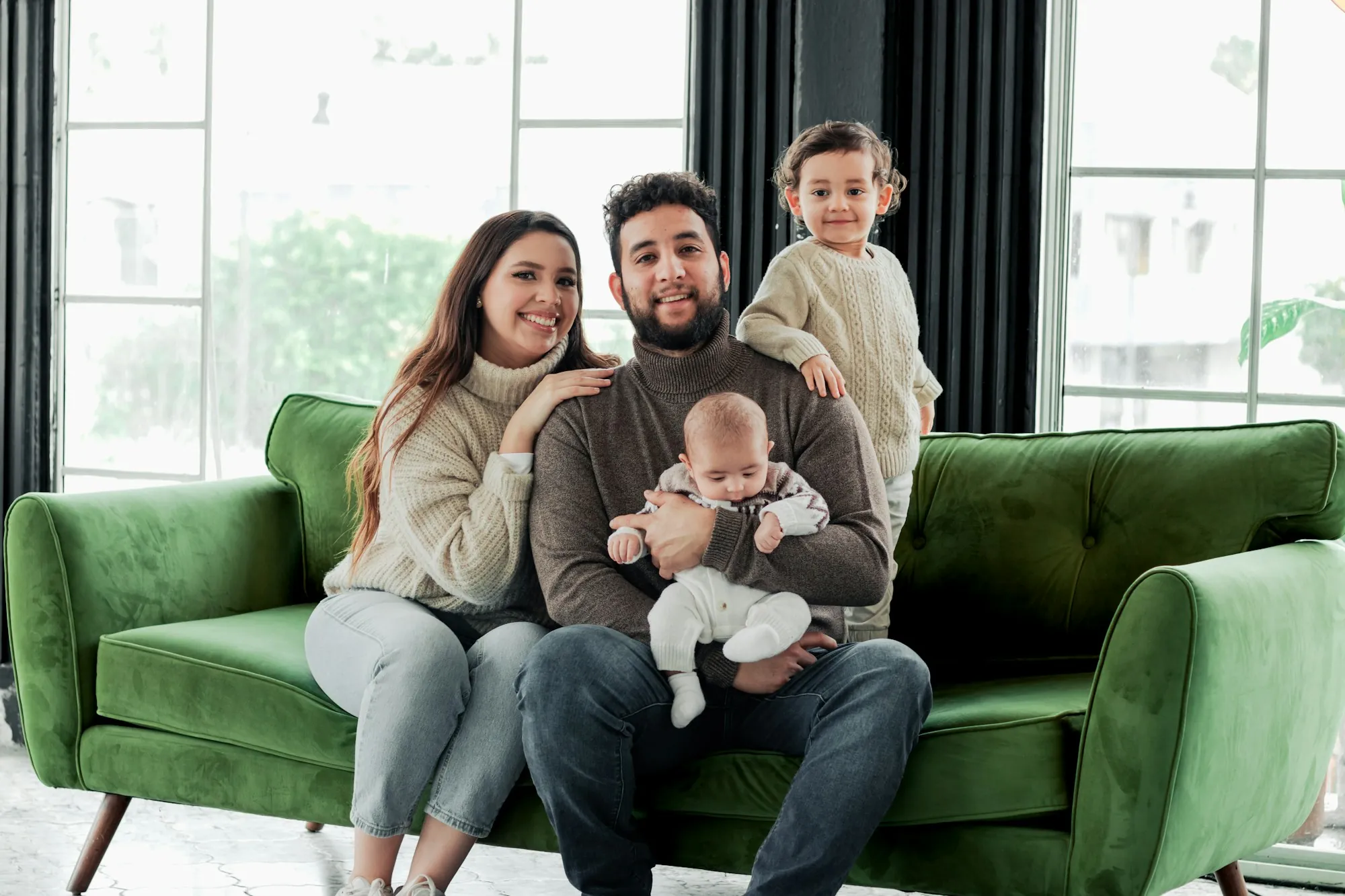 Parents with a baby and a toddler sitting on a green sofa
