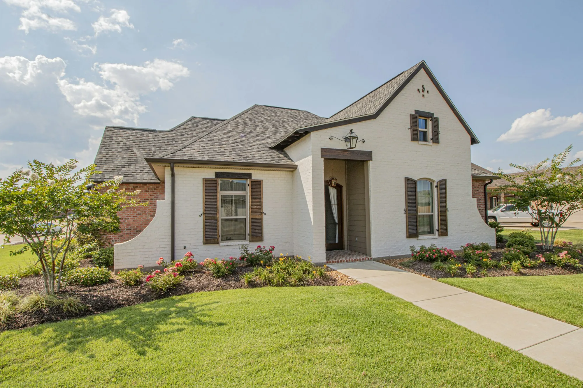 Cream stucco house with shutters and a landscaped front walk